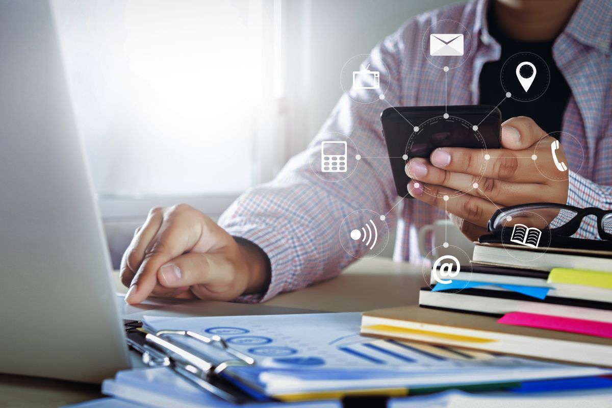 man on his phone and checking details on his laptop