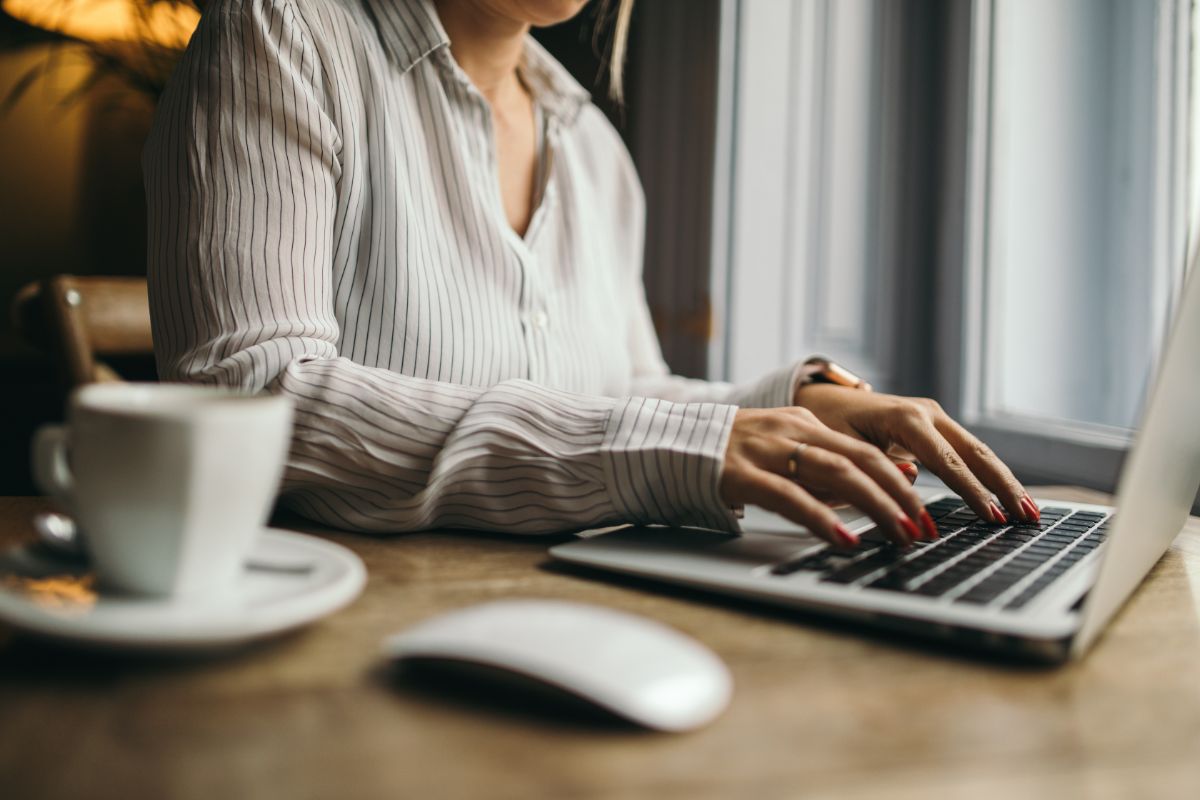 woman working on her laptop with a cup of coffee on the side