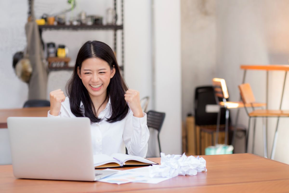 asian woman excitedly looking at her laptop