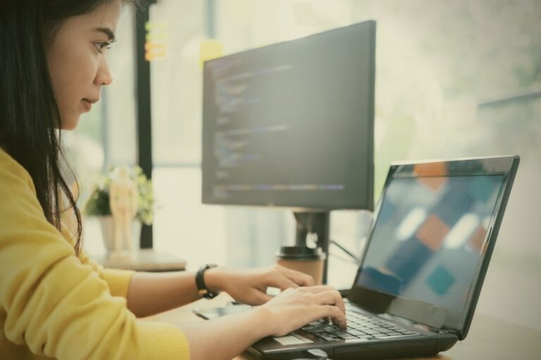 woman in yellow focused on her computer doing code