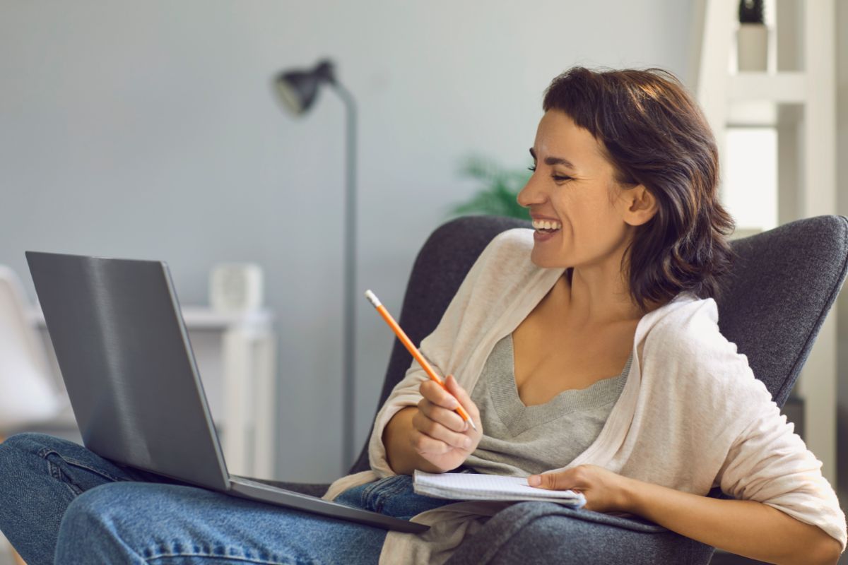 woman working remotely sitting on a couch taking notes on her client call