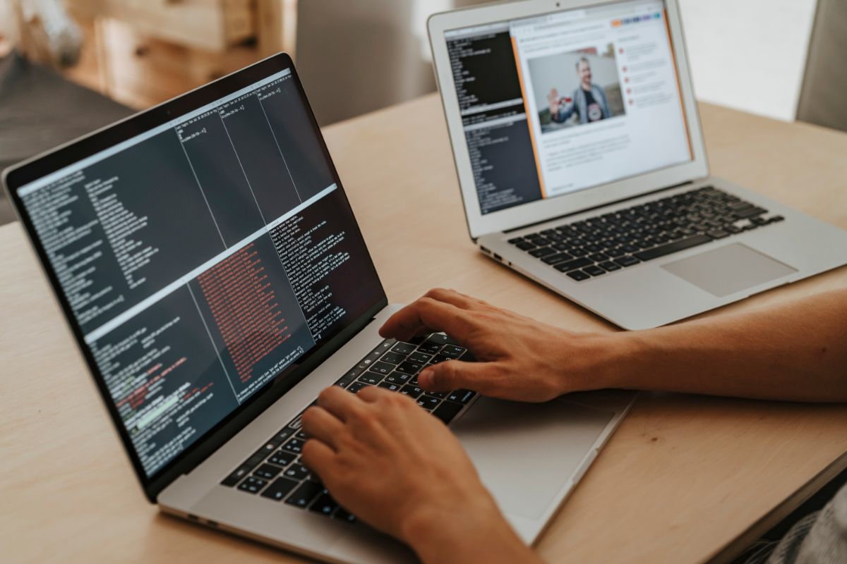 a man on two computers working on programming codes