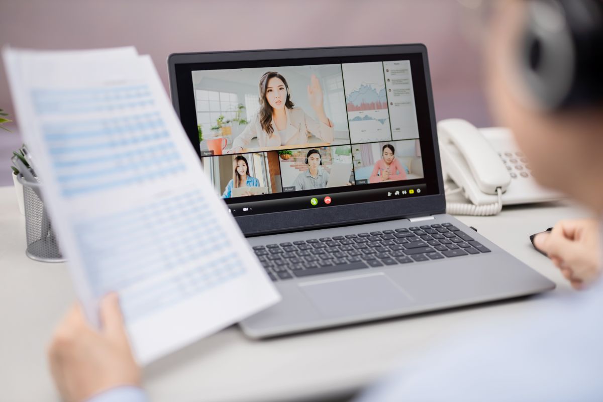 a man holding a report while on a video call with someone