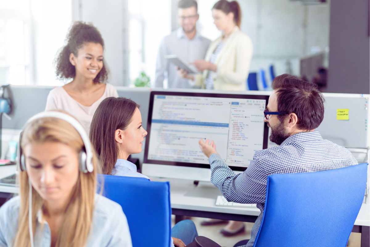 employees in an office in the center a trainer is coaching a trainee