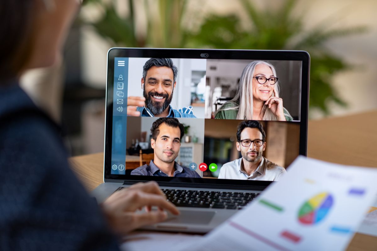 woman holding metric charts having a video call with co workers