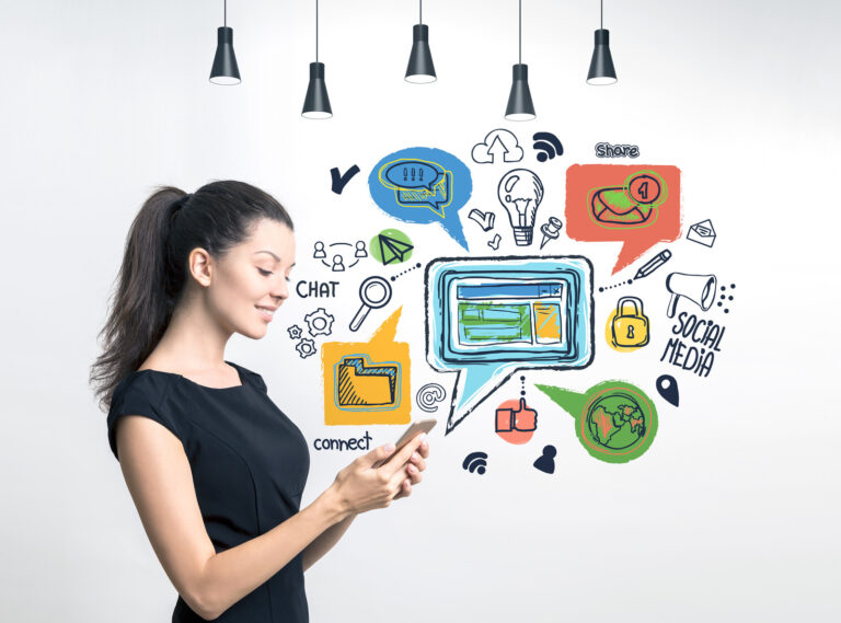 Side view of smiling young woman wearing black dress looking at her smartphone screen standing near concrete wall with colorful social media icons drawn on it.