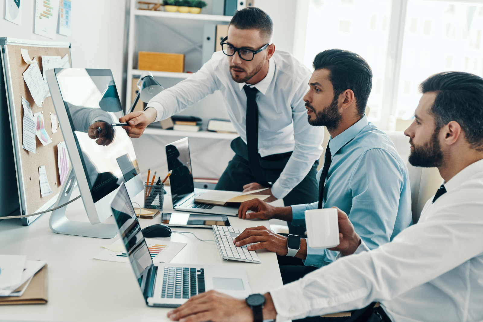 Group of young modern men in formalwear working using computers while sitting in the office