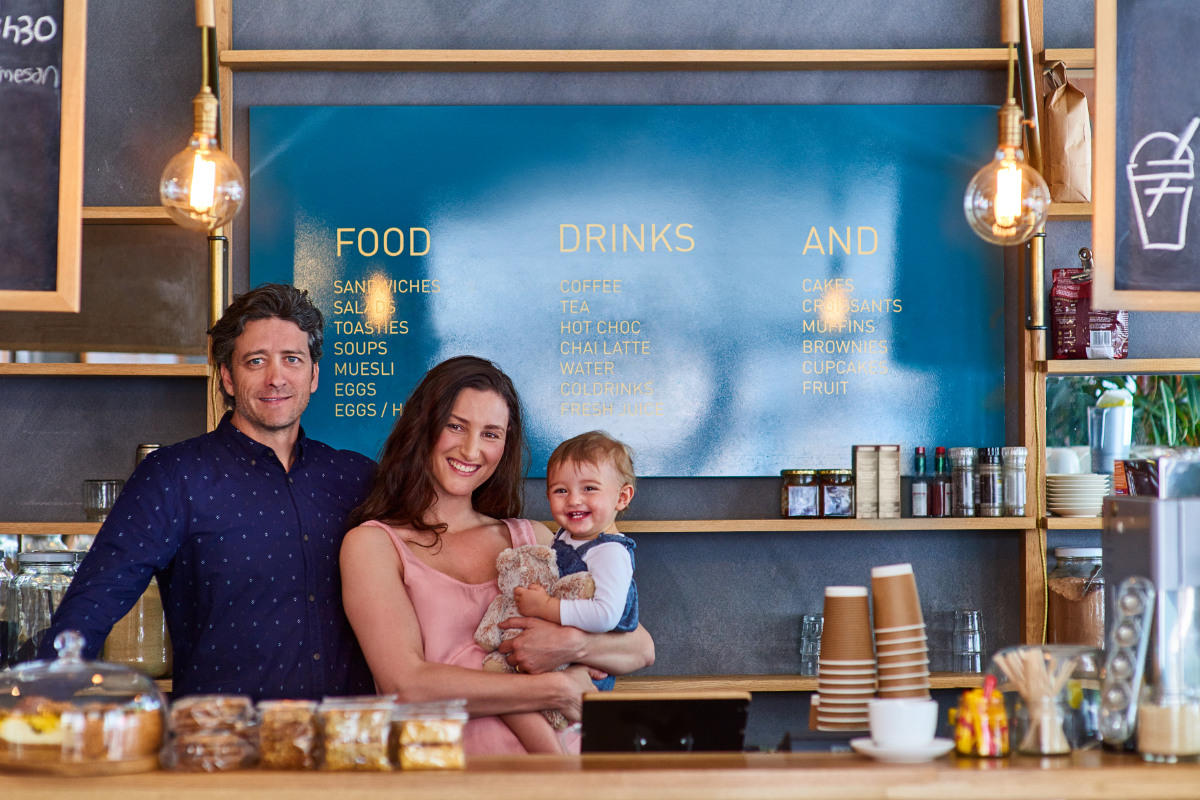 Family of 3 posing in front of the family business menu