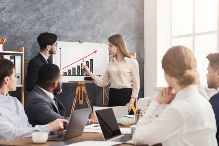 Man and woman leading a meeting with a white board showing an upward graph showcasing the growth of the company